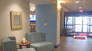 A lobby with two patterned armchairs, a small table with a candle, and a patterned rug. - Hampton Inn & Suites Wiggins (Wiggins)