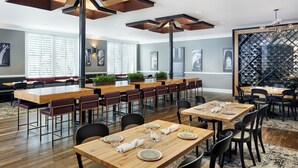 A spacious dining area with multiple wooden tables and chairs, a large wine rack, and a seating area with cushioned benches. - Inn at Carnall Hall (Fayetteville)