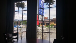 Vista a través de amplios ventanales de un edificio con letrero de hotel, un puente y un estacionamiento.