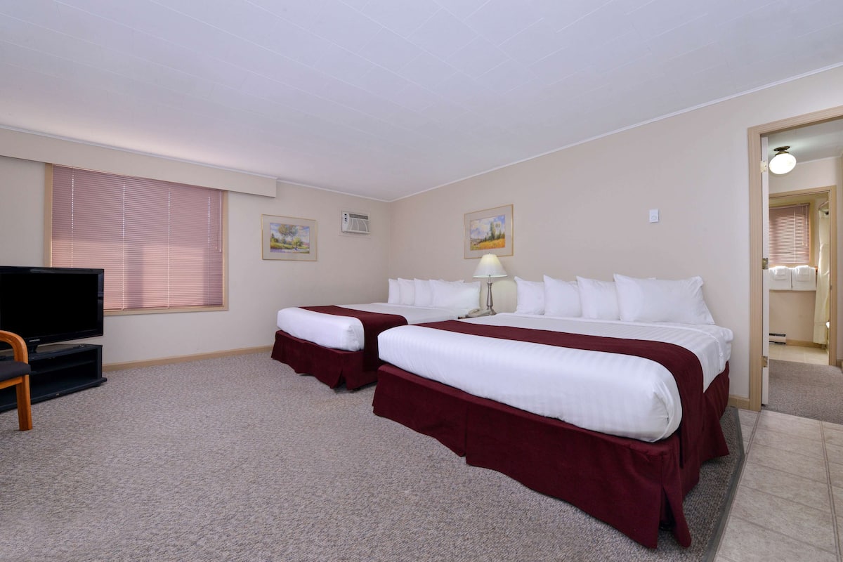 A hotel room with two beds, a television, and a desk.