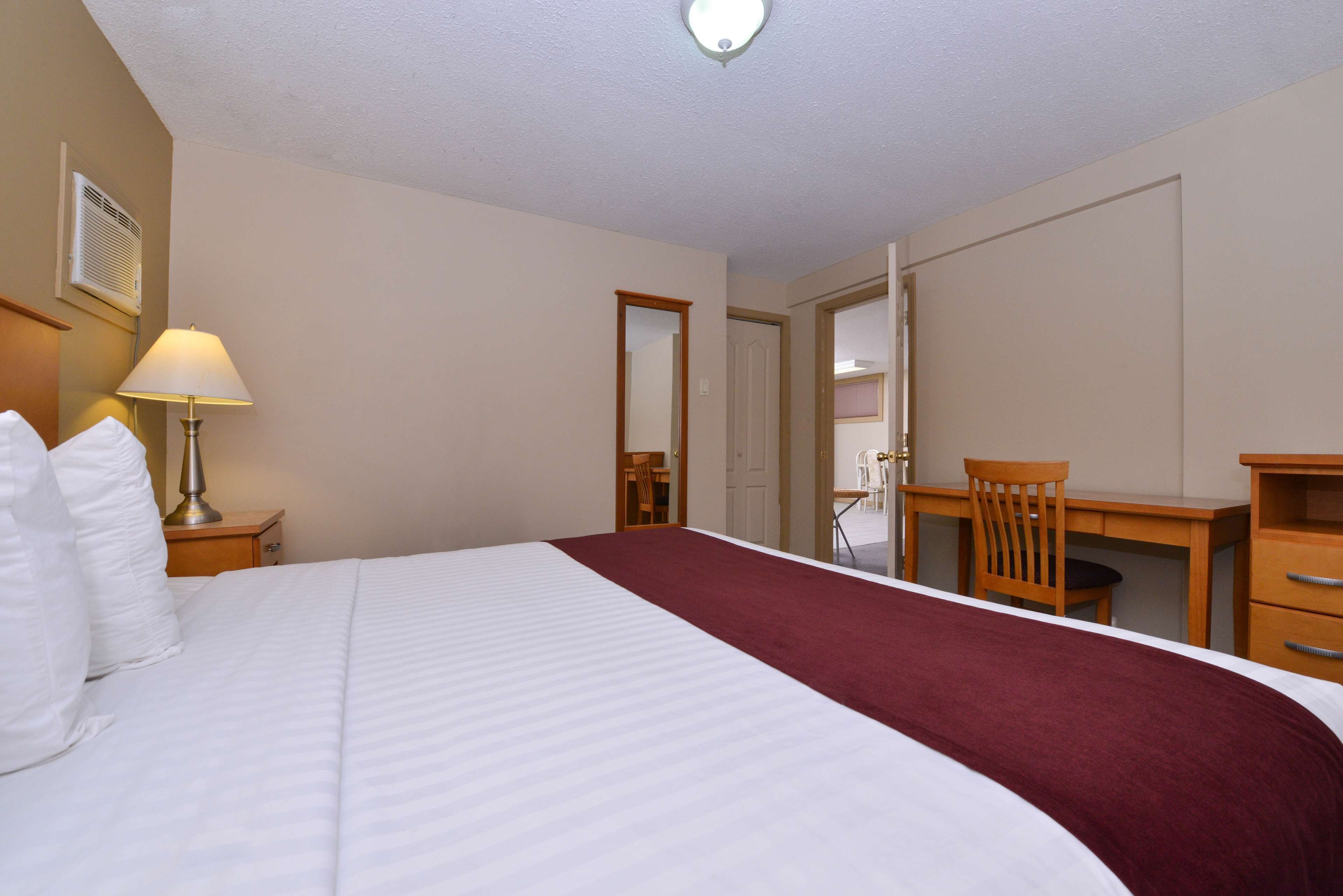 Una habitación de hotel con una cama grande, un escritorio, una silla y una lámpara.