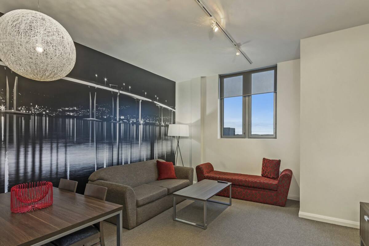 Una sala de estar moderna con un mural grande, una mesa de comedor, un sofá y una mesa de centro.