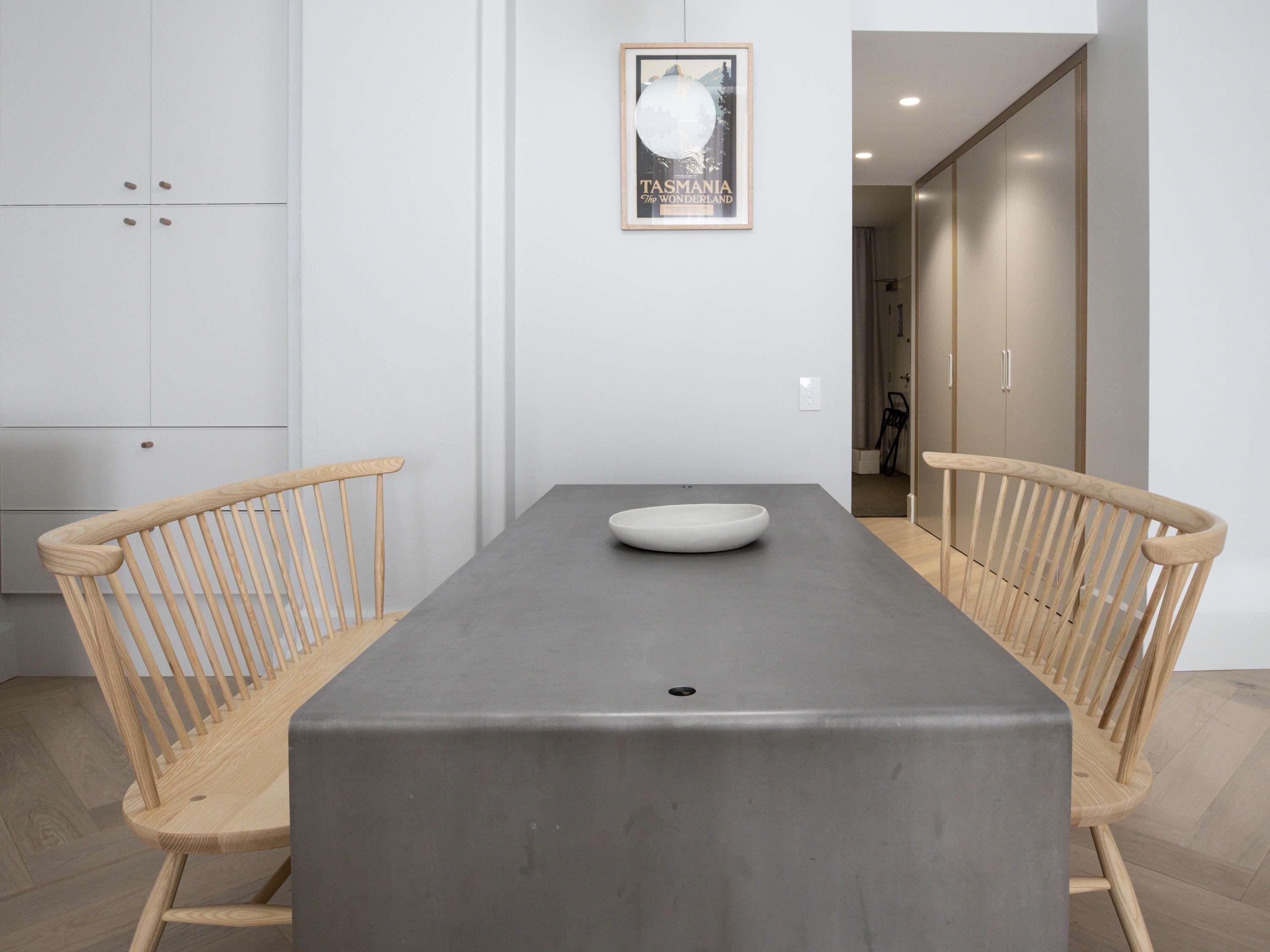 Un espace repas moderne avec une table rectangulaire, deux chaises en bois et un bol blanc.