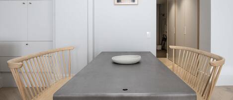 Un espace repas moderne avec une table rectangulaire, deux chaises en bois et un bol blanc.