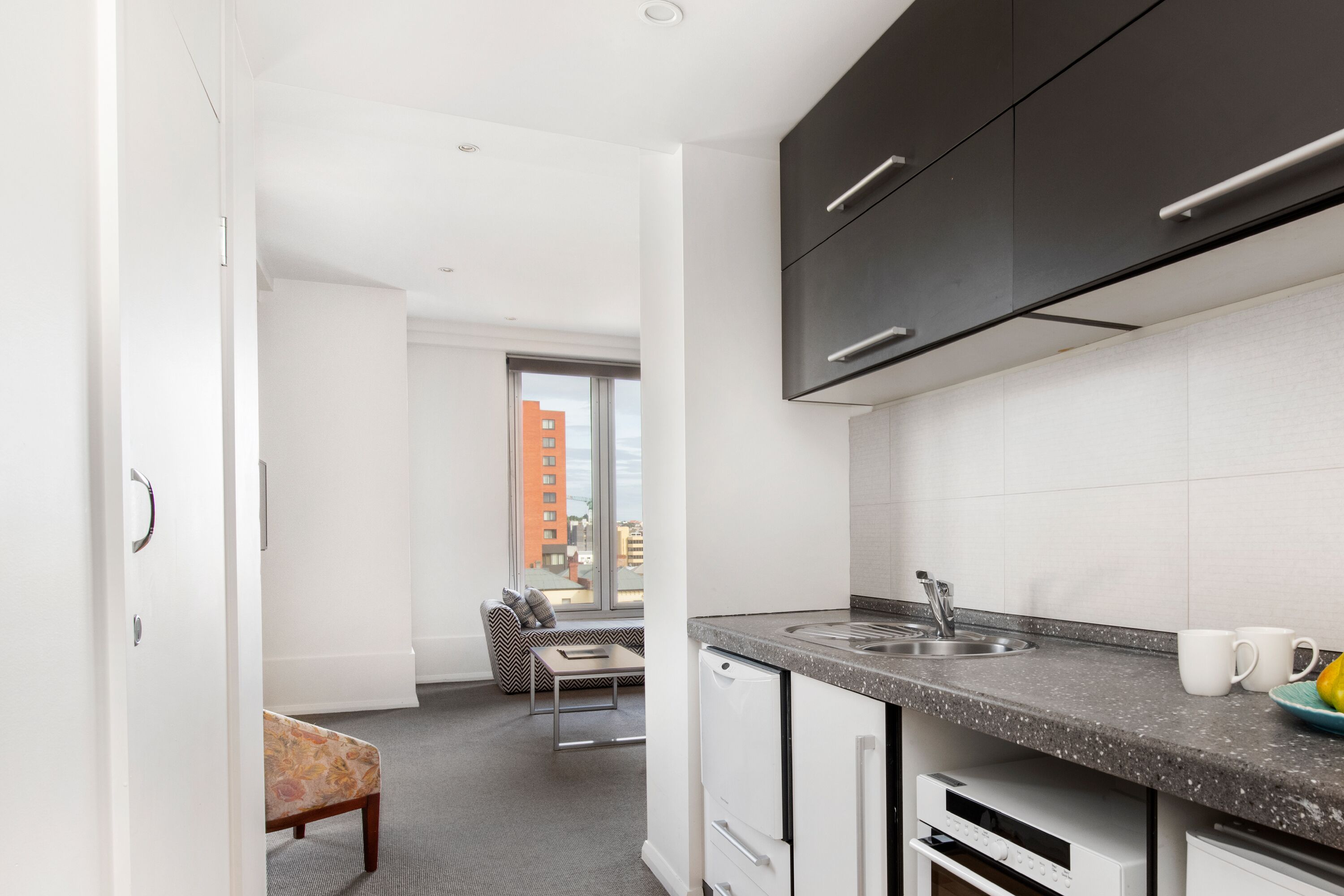 A modern kitchen with a built-in dishwasher, a sink, and a window overlooking a cityscape.