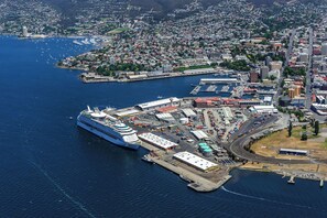 Um grande navio de cruzeiro atracado em um porto, com um horizonte urbano ao fundo.