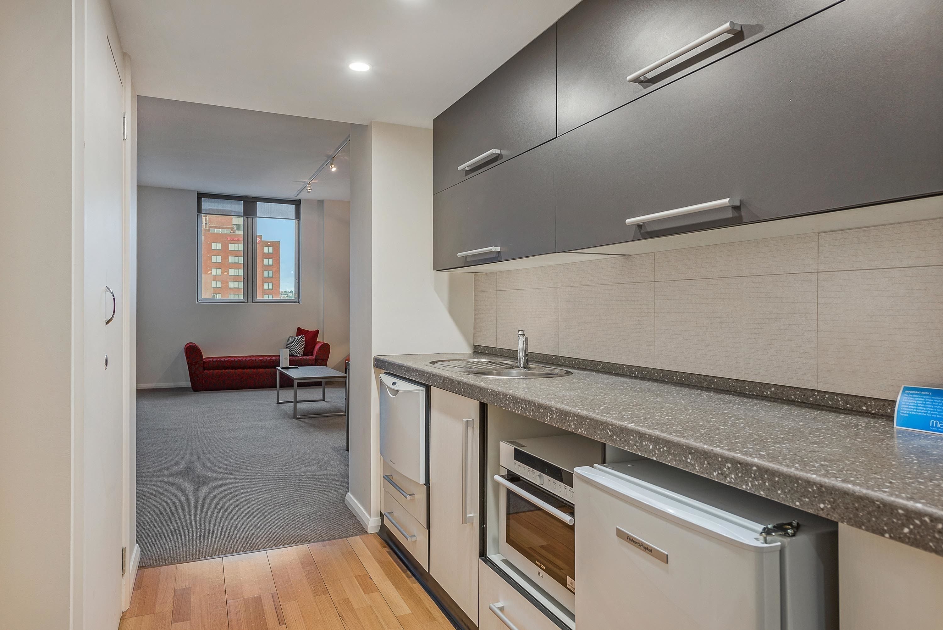 Eine moderne Küche mit grauen Schränken, einer Granit Arbeitsplatte und eingebauten Geräten.