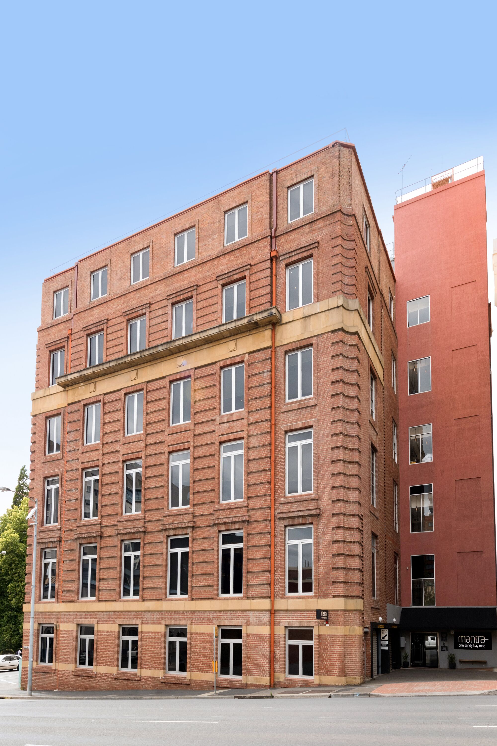 Un edificio de varios pisos de ladrillo, con fachada plana, ventanas amplias y entrada a nivel de calle.