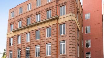 Un edificio de varios pisos de ladrillo, con fachada plana, ventanas amplias y entrada a nivel de calle.