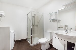 Uma casa de banho moderna com cabine de duche em vidro, sanita branca e lavatório com espelho.