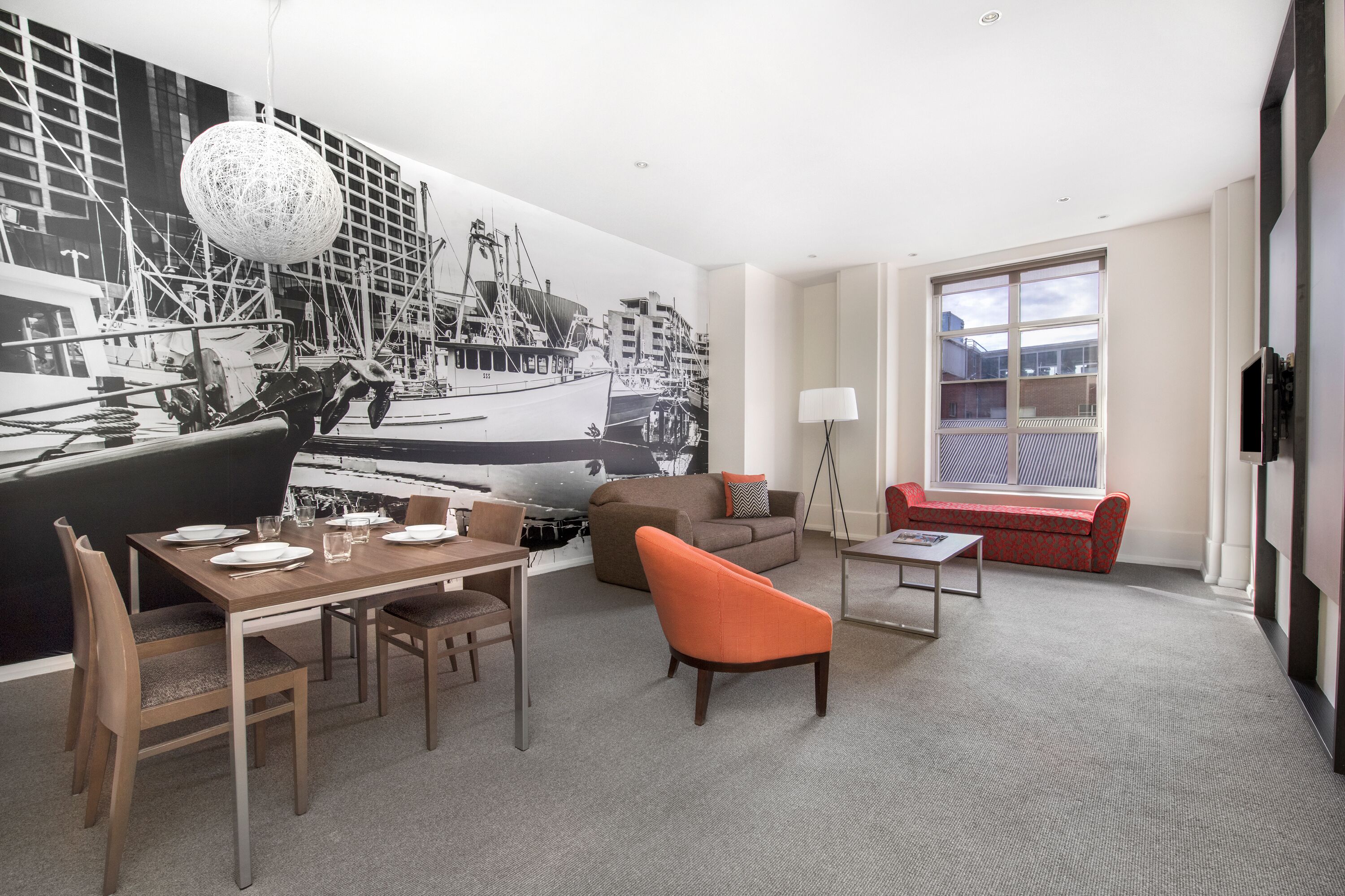 Ein modernes Hotelzimmer mit Essbereich, einer Couch und einem roten Sessel.