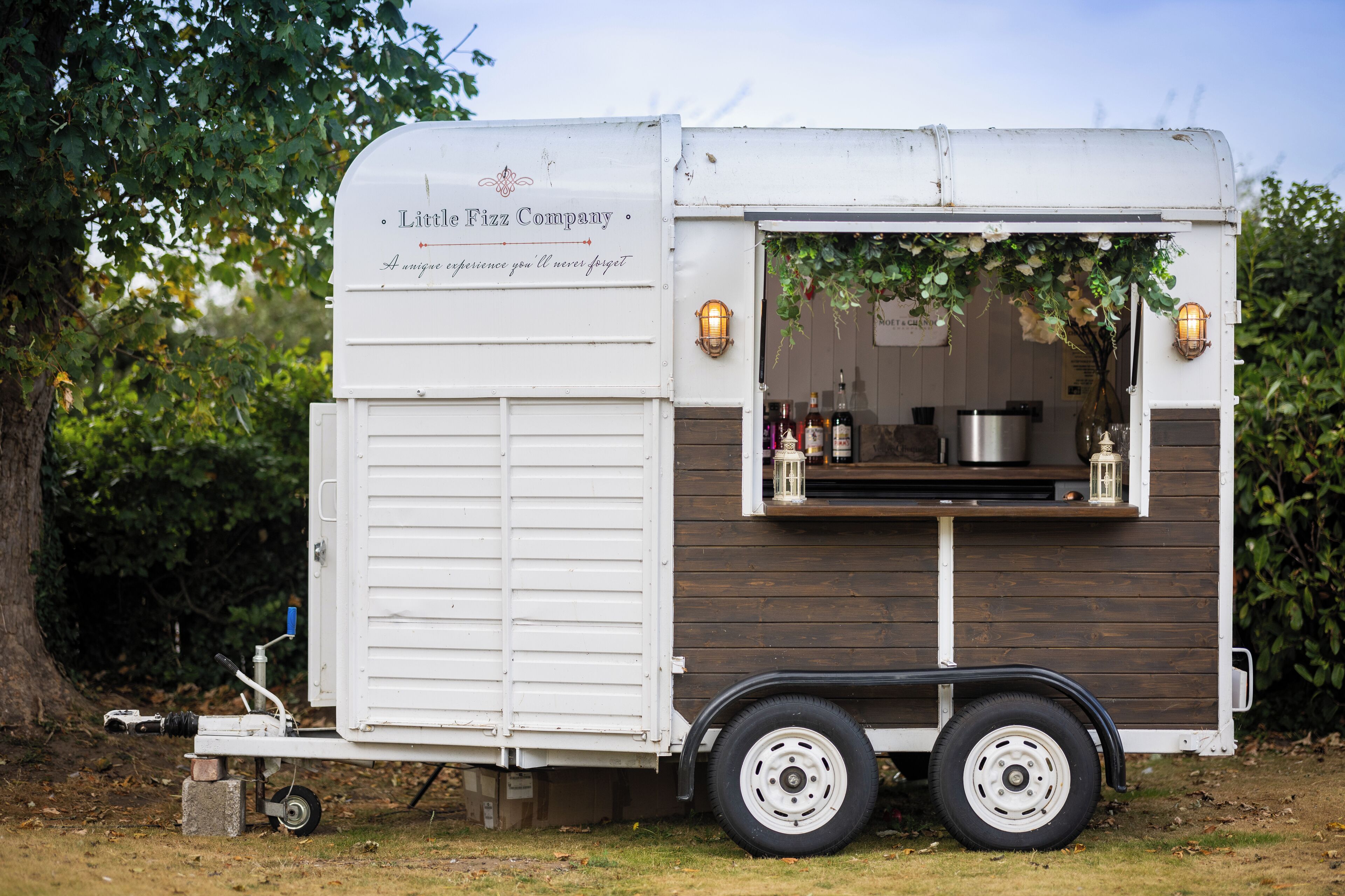 A food truck with a white and brown exterior, a serving window, and a small kitchen area visible through the window.