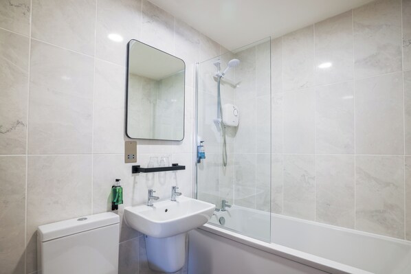 A modern bathroom with a glass-enclosed shower, a white sink, and a toilet.