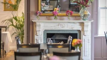 A dining area with a fireplace, chairs, and tables set for a meal.