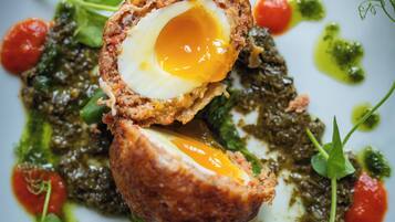 A plate of food with a poached egg, greens, and tomatoes.