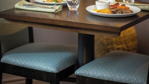 Mesa de jantar posta com pratos, copos e um vaso de flores.