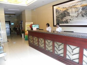 A reception desk with two staff members, a large framed painting of a waterfall, and a digital screen displaying information. - GreenTree Inn Changzhou Xinbei District Taihu Road Wanda Square Express Hotel (Changzhou)