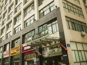 Un hôtel à plusieurs étages, une enseigne indiquant le « Green Tree Inn », et divers commerces situés au rez-de-chaussée.