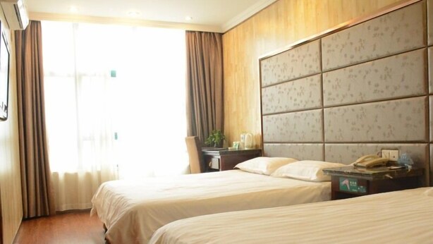 A hotel room with two beds, a wooden headboard, a bedside table with a lamp, and a window with curtains. - GreenTree Inn Changzhou Xinbei District Taihu Road Wanda Square Express Hotel (Changzhou)