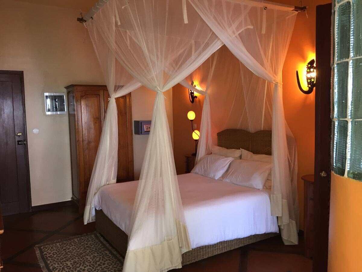 Un dormitorio con cama con dosel, una mesita de noche, una lámpara de pared y una puerta.