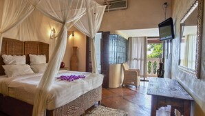 A bedroom with a canopy bed, a television, and a view of the outdoors. - Catembe Gallery Hotel (Maputo)