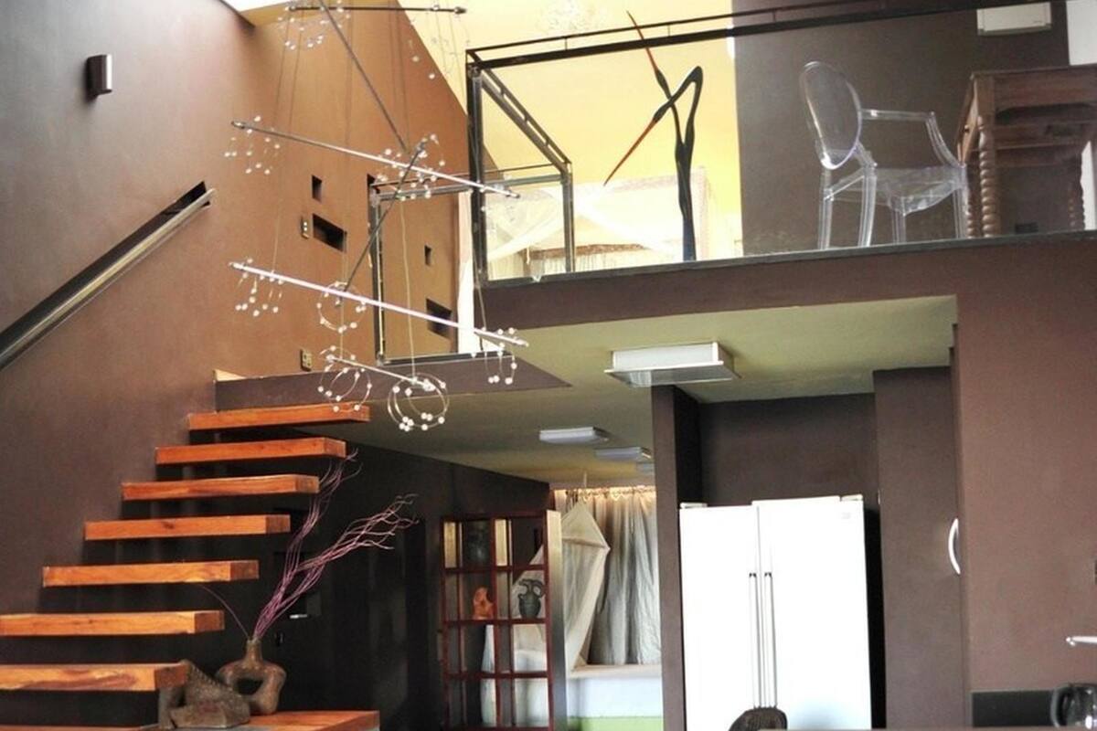 A modern interior with a wooden staircase, a glass railing, and a high ceiling with a skylight.