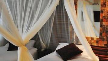 A bed with a canopy and a headboard, a wall with a patterned design, and a mirror.