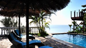 A poolside area with lounge chairs and a view of the ocean. - Catembe Gallery Hotel (Maputo)