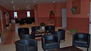 A lobby with black leather chairs, a coffee table, and a reception desk. - Timon (Budapest)