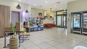 Un vestíbulo moderno con mostrador de recepción, zona de estar, máquinas expendedoras y diversas comodidades.
