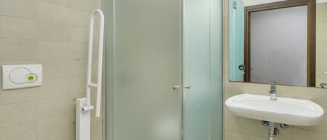 A modern bathroom with a glass-enclosed shower, a white toilet, and a sink with a mirror above it.