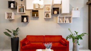 Una sala de estar moderna con un sofá rojo, una mesa de centro y varios estantes y jarrones en la pared.