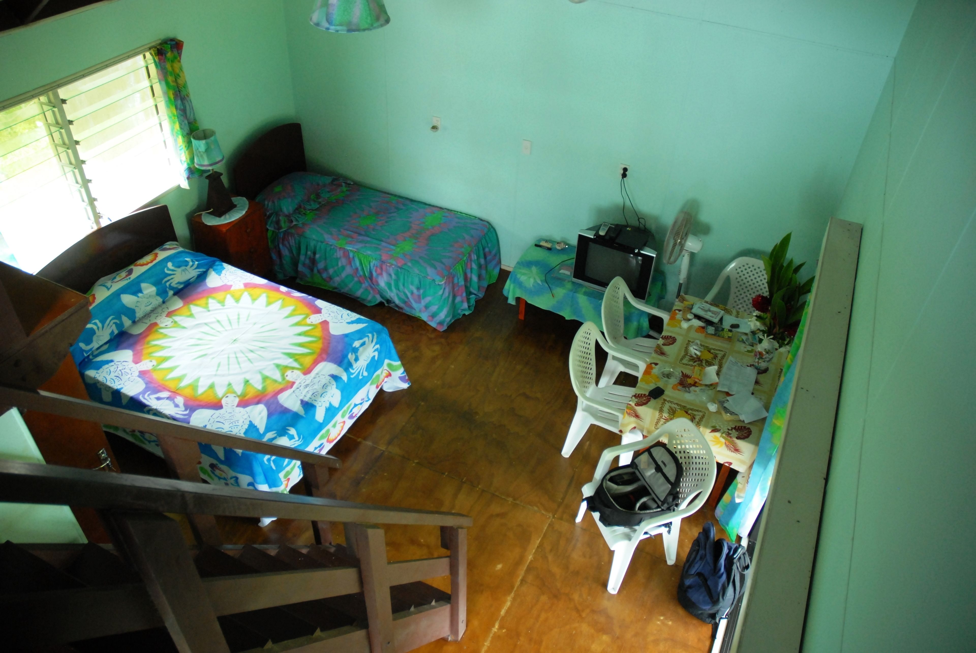 A room with a bed, a desk with a computer, a chair, and a staircase.