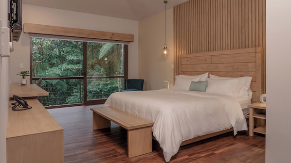 A bedroom with a large window, wooden headboard, and a bedside table. - El Silencio Lodge and Spa (Toro Amarillo)