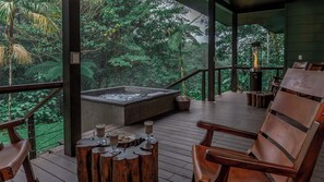 A wooden deck with a hot tub, wooden chairs, and a view of lush greenery. - El Silencio Lodge and Spa (Toro Amarillo)