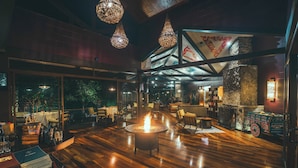 A spacious indoor area with a central fire feature, wooden flooring, and hanging light fixtures. - El Silencio Lodge and Spa (Toro Amarillo)