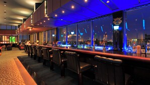 A bar area with a city view, bar stools, and bottles. - Navios Yokohama (Yokohama)