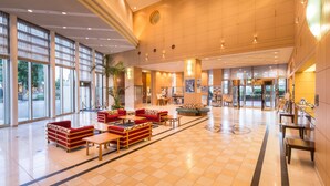 A spacious lobby with large windows, a central seating area with sofas and tables, and a reception desk. - Navios Yokohama (Yokohama)