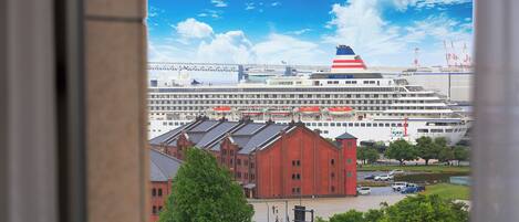 A large cruise ship docked at a port with a red building in the foreground.