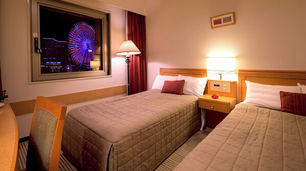 Une chambre d’hôtel avec deux lits, une table de chevet, une lampe, une fenêtre donnant sur une grande roue et une horloge murale.