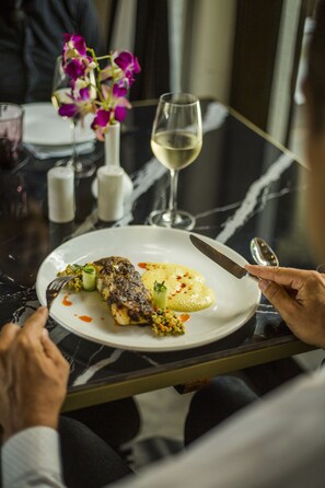 A dining table with a plate of food, a wine glass, and a vase of flowers. - Sol De Goa by Sereno (Nerul)