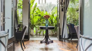 A room with a round table, chairs, and a potted plant with flowers. - Sol De Goa by Sereno (Nerul)