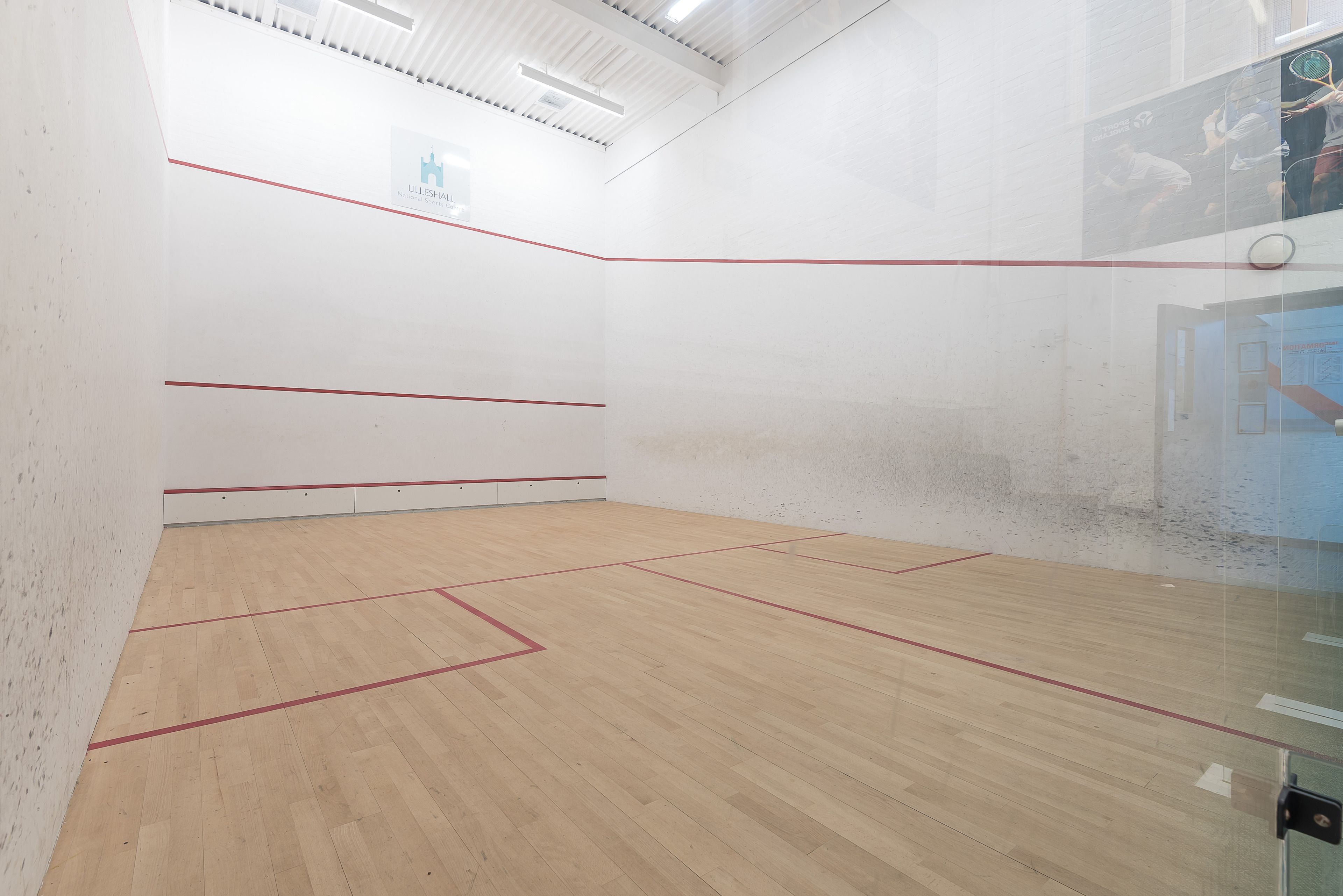 Squash-kenttä, jossa on puulattia ja punaiset rajaviivat.