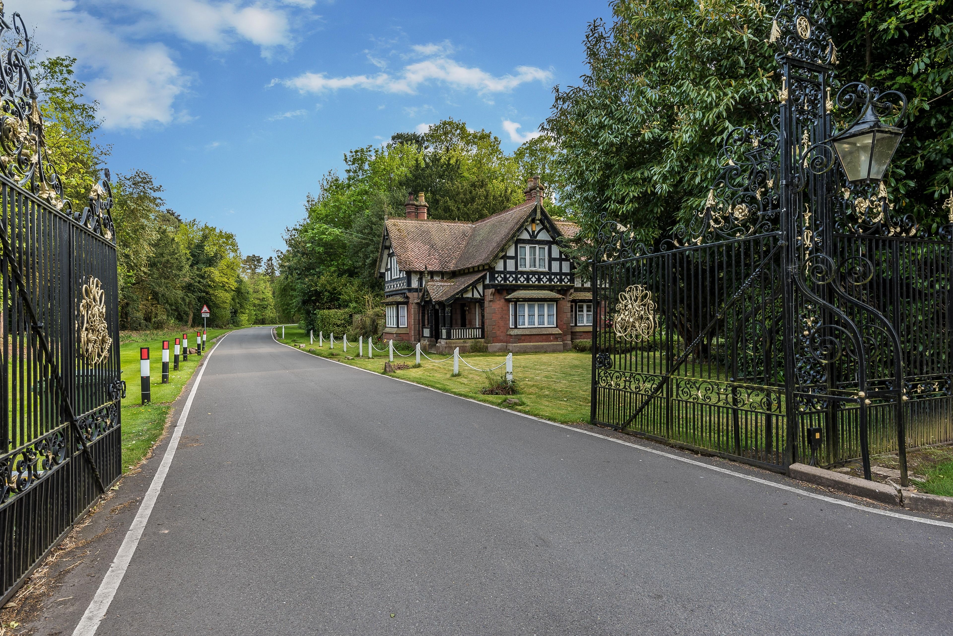 Una casa de estilo Tudor con un camino pavimentado que conduce a un acceso con puerta.