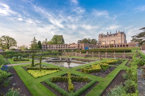 A historic building with a formal garden, including a central fountain and geometrically shaped hedges. - Lilleshall National Sports Centre (Newport)