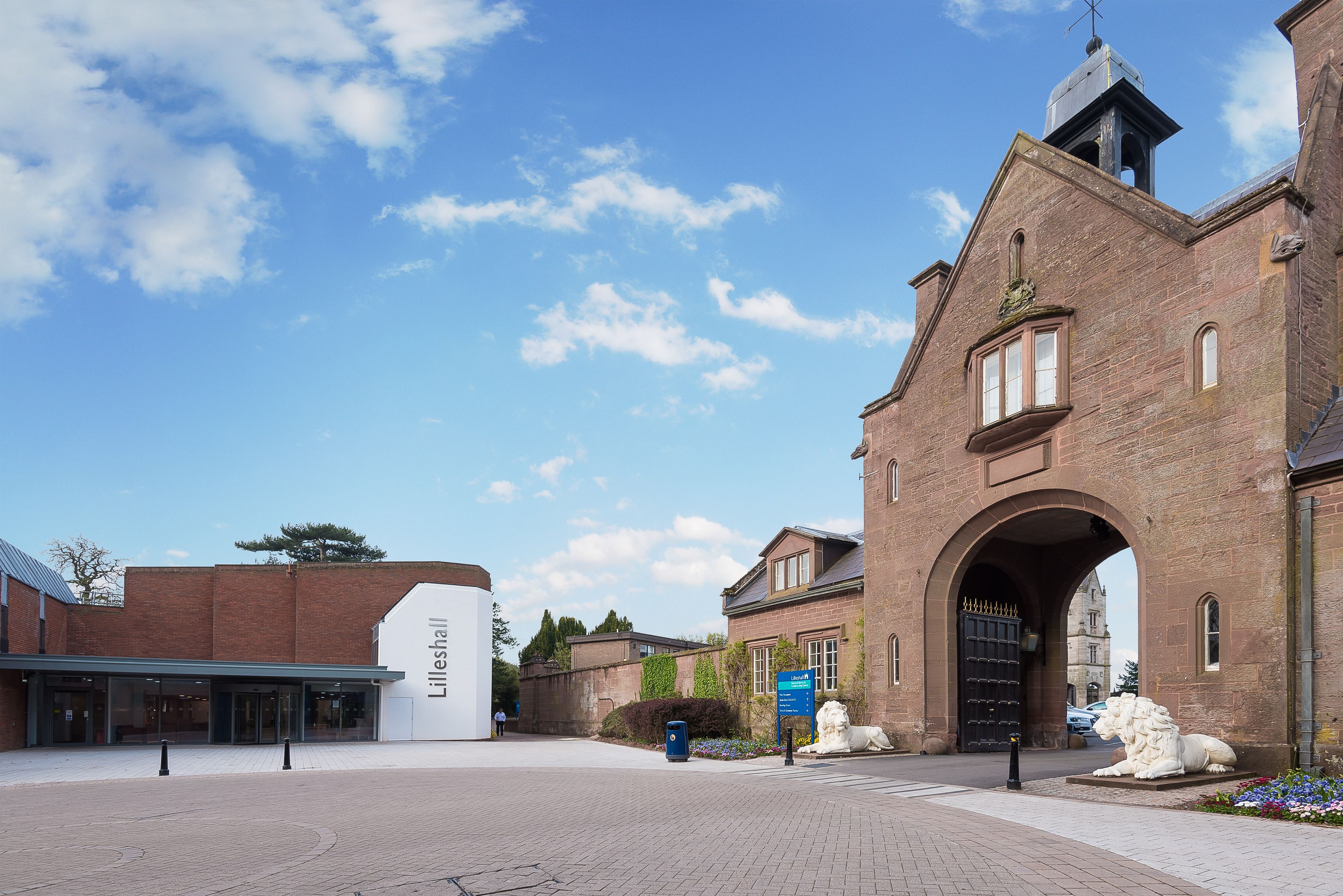 Un edificio histórico con una entrada en arco, una torre de campanas y una estatua de león.