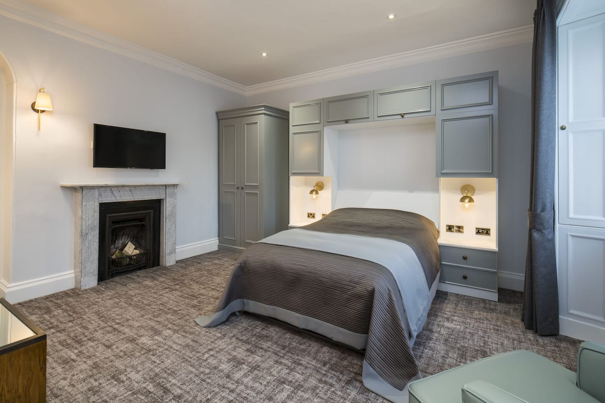 A bedroom with a fireplace, a bed, a television, and built-in cabinets.