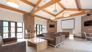 A spacious room with a wooden ceiling, a large screen, and comfortable seating. - Lilleshall National Sports Centre  (Newport)