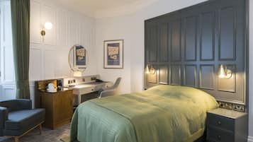 Een hotelkamer met een bed, bureau, stoel en nachtkastje.