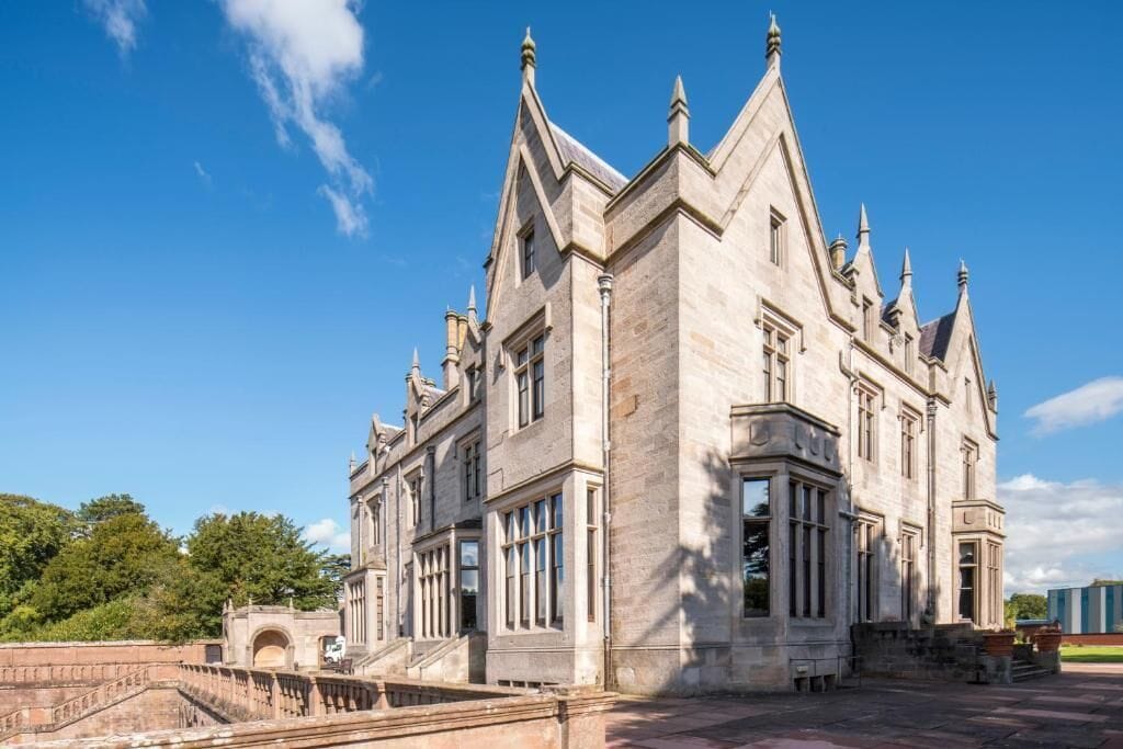 A large, historic building with a prominent central tower and multiple windows.